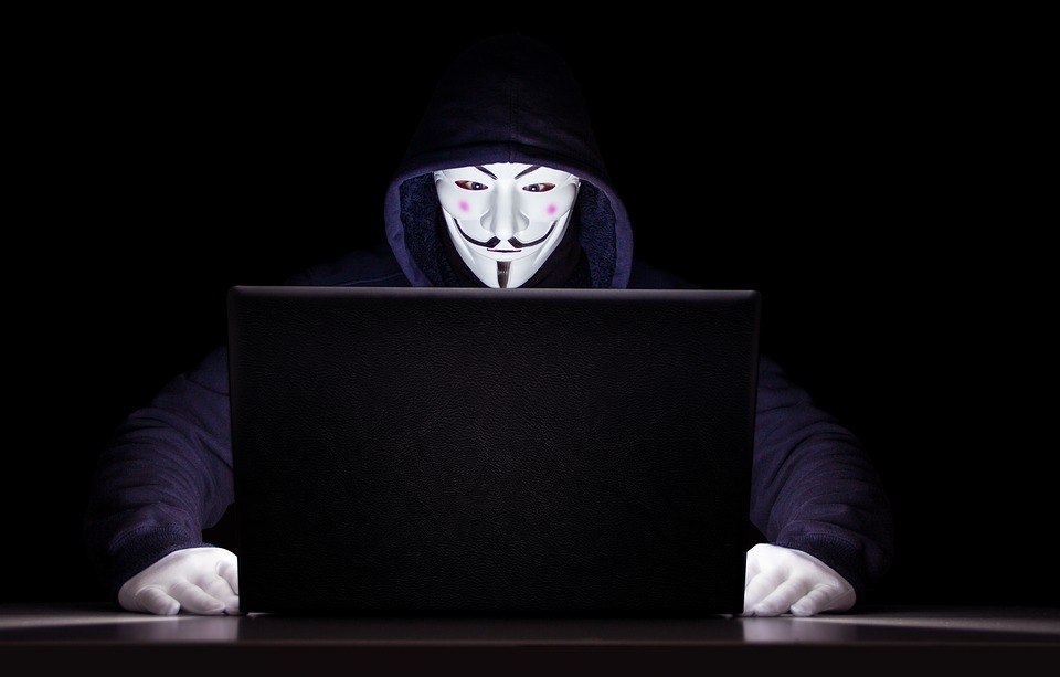 Masked man using laptop computer to commit crime